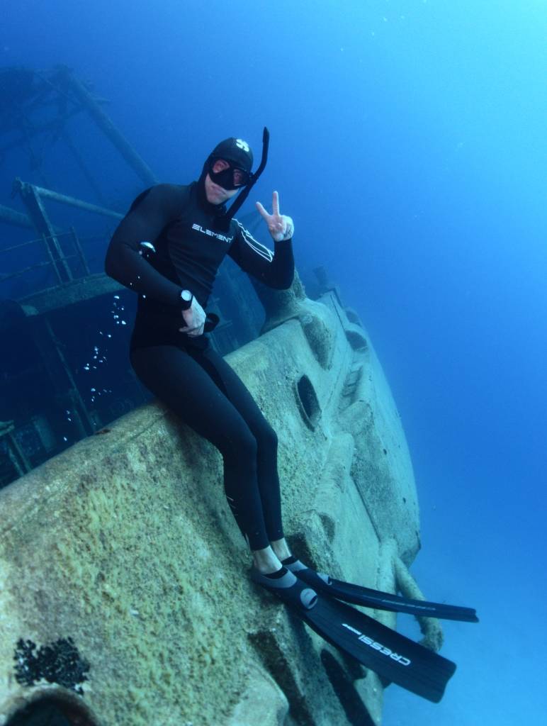 Freediver sitting on a shipwreck